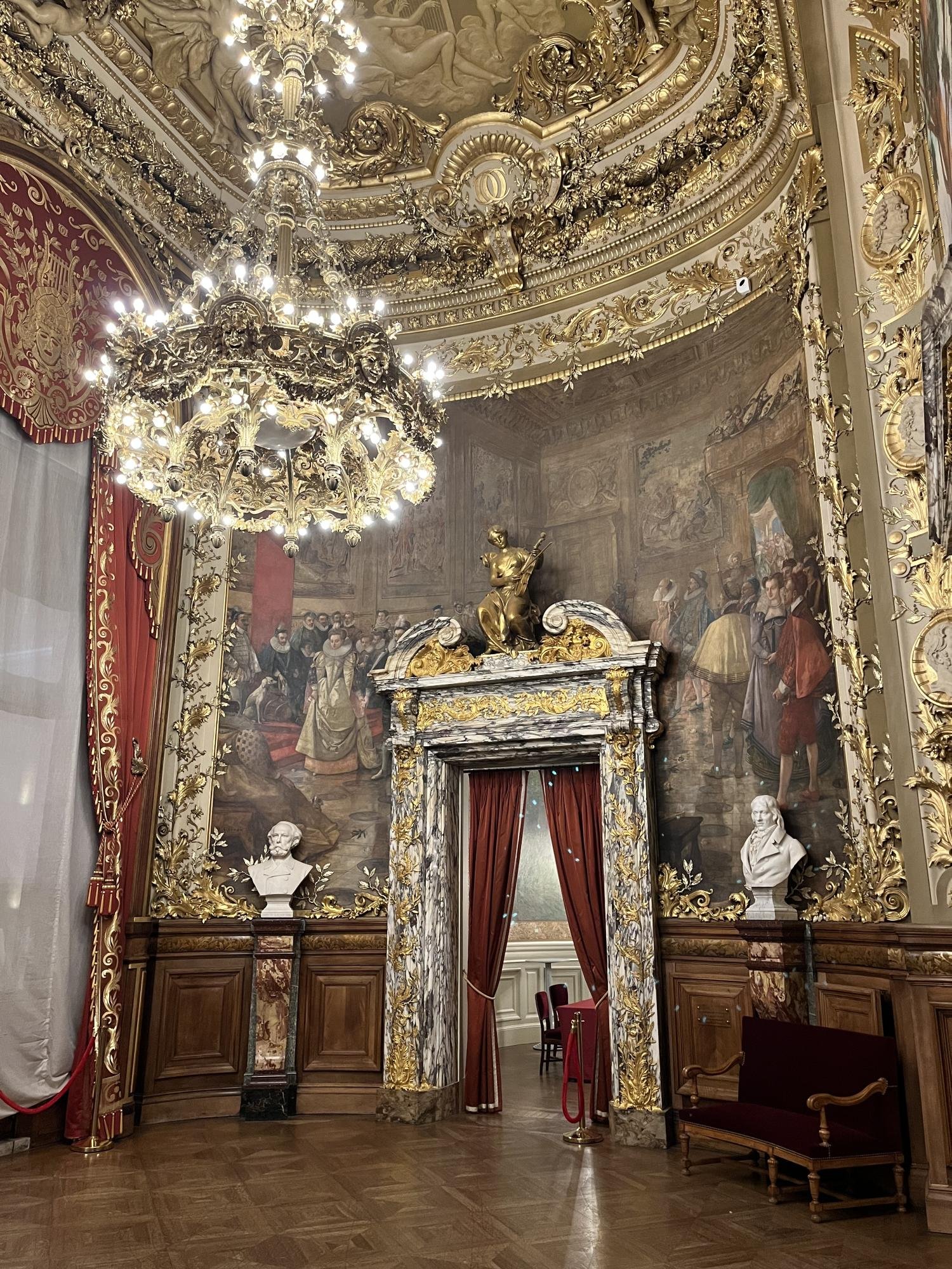 Dans l'Opéra Comique, le foyer accueille les spectateurs dans un espace riche en peintures et en or.